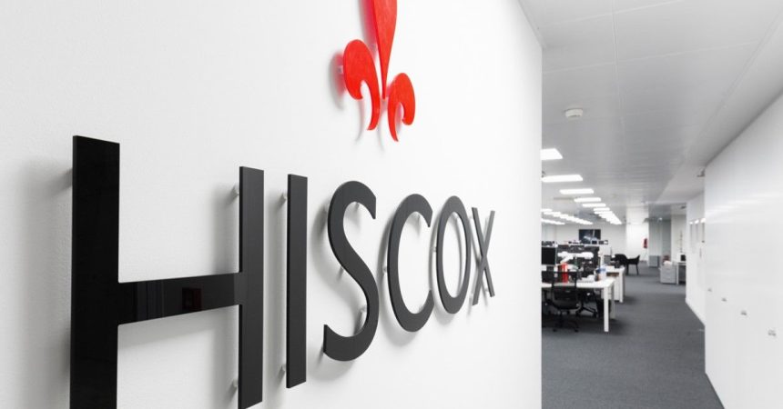 Escritório moderno da HISCOX com design minimalista, logo preto e flor de lis vermelha.