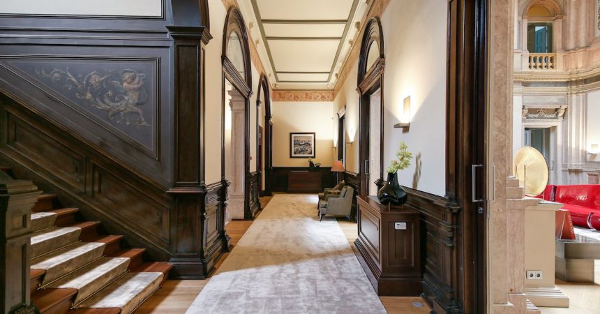 Interior clássico-contemporâneo com escadaria elegante, corredor com arcos e sala com móveis vermelhos.